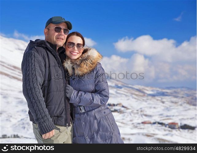 Portrait of cute loving couple walking in snowy mountains, active lifestyle, wintertime adventure, cold weather, enjoying winter holidays