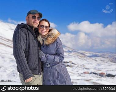 Portrait of cute loving couple walking in snowy mountains, active lifestyle, wintertime adventure, cold weather, enjoying winter holidays