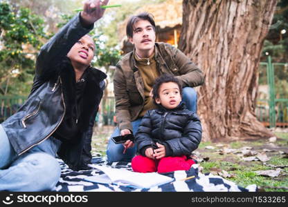 Portrait of cute mixed race ethnic family having a good time together at the park outdoors.