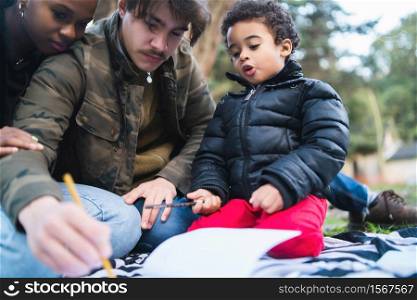 Portrait of cute mixed race ethnic family having a good time together at the park outdoors.