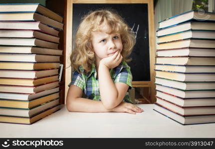 Portrait of cute schoolgirl thinking while sitting with stack of books at table, education concept