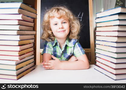 Portrait of cute smart girl smiling while sitting with stack of books at table