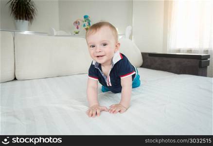 Portrait of cute smiling baby boy crawling on bed and looking in camera. Portrait of smiling baby boy crawling on bed and looking in camera