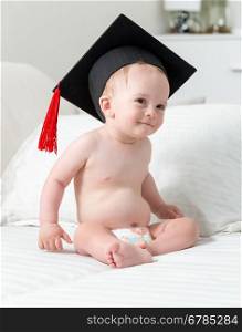 Portrait of cute smiling baby boy in diapers and graduation cap