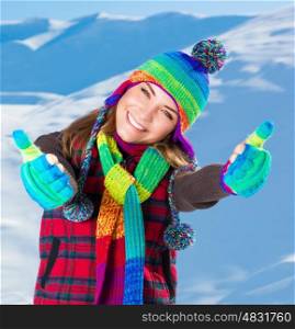 Portrait of cute smiling girl gesturing by hands good mood, wearing stylish colorful outfit, spending active winter holidays in the snowy mountains