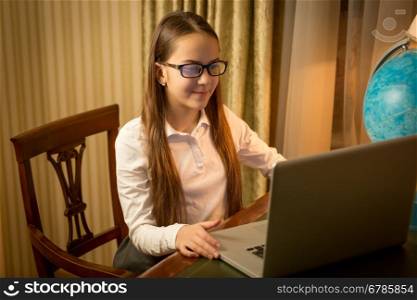 Portrait of cute smiling girl typing message on laptop