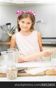 Portrait of cute smiling girl with rolling pin making dough