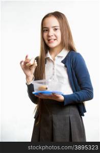 Portrait of cute smiling schoolgirl holding sandwich against white background