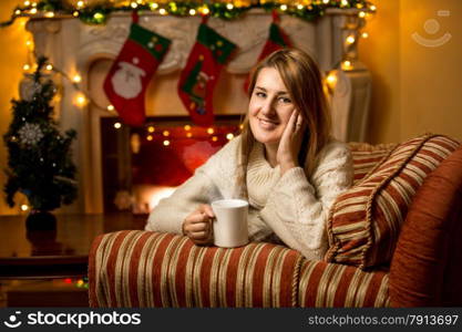 Portrait of cute smiling woman holding cup of tea at fireplace