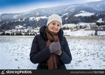 Portrait of cute smiling woman posing against high snowy mountains
