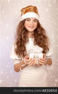 Portrait of cute teen girl with Christmas gift on snowy background, wearing funny Santa hat, celebrating New year&#xA;