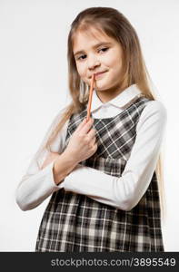 Portrait of cute thoughtful schoolgirl chewing pencil against white background