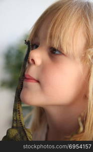 Portrait of cute young girl with blond hair playing with rubber dinosaur