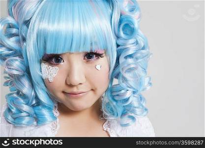 Portrait of cute young woman in doll costume over gray background