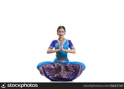 Portrait of dancer greeting while performing Bharatanatyam against white background