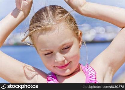 Portrait of dancing girl on the riverbank in pink swimsuit