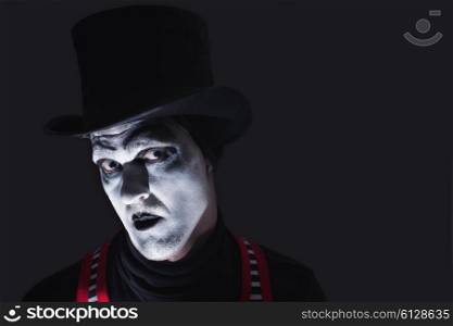 Portrait of dark angry mime wearing tall hat