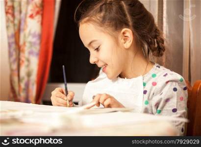 Portrait of diligent girl doing drawings with brush