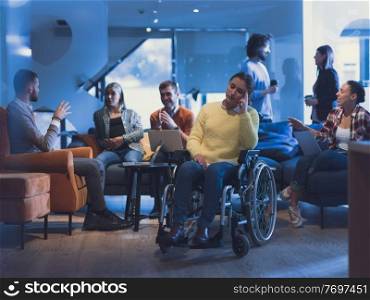 Portrait of disabled businesswoman in a wheelchair in front of her diverse business team in a modern open space coworking office space. High quality photo. Portrait of disabled businesswoman in a wheelchair in front of her diverse business team at office