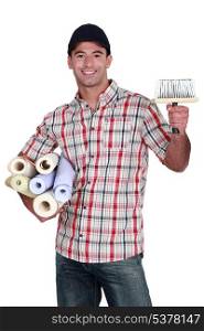 portrait of do-it-yourselfer carrying wallpaper rolls and brush