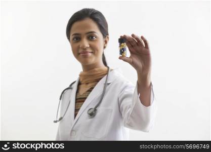 Portrait of doctor holding pill bottle isolated over white background