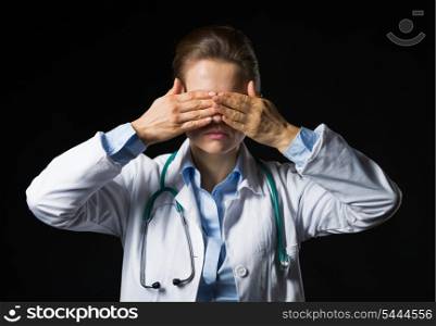 Portrait of doctor woman showing see no evil gesture isolated on black