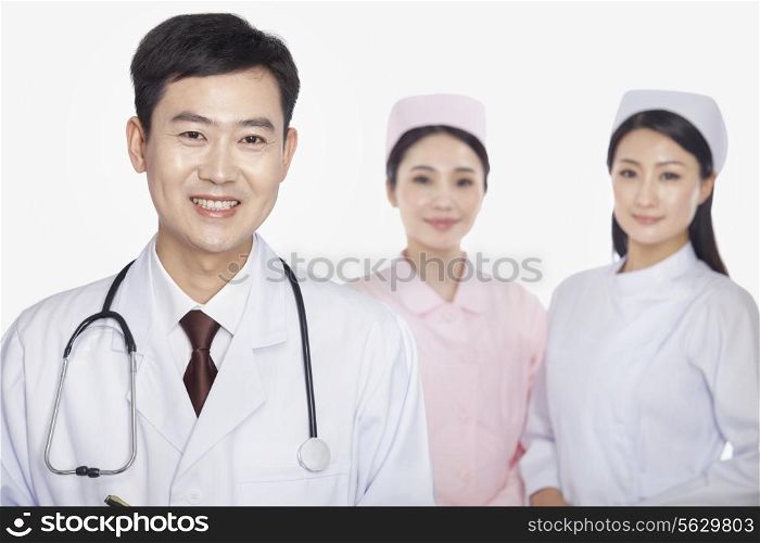 Portrait of doctor, young nurses in background, studio shot