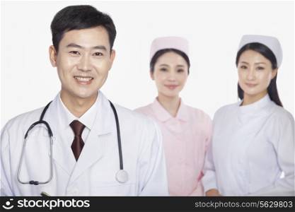 Portrait of doctor, young nurses in background, studio shot