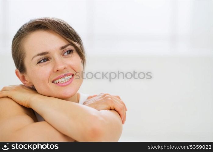 Portrait of dreaming woman sitting on bed and looking on copy space