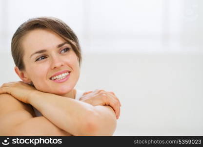 Portrait of dreaming woman sitting on bed and looking on copy space