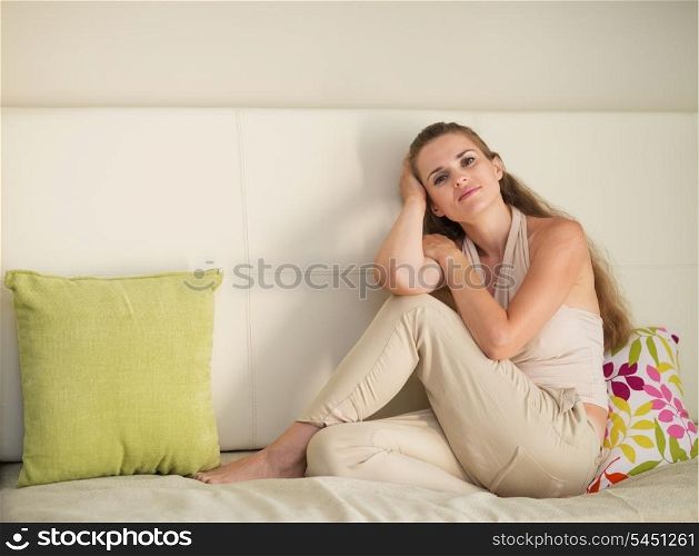 Portrait of dreaming young woman sitting on couch