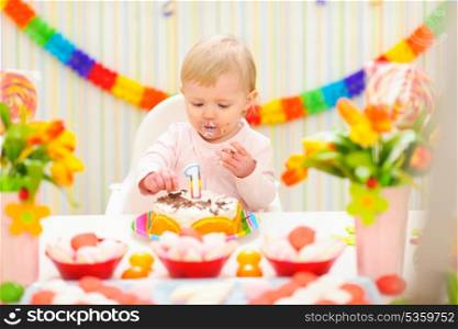Portrait of eat smeared baby eating birthday cake