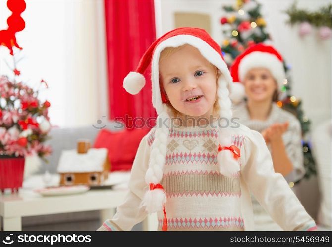 Portrait of eat smeared baby girl in Christmas hats dancing