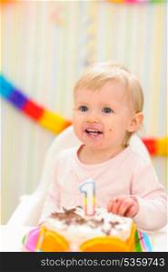 Portrait of eat smeared baby with birthday cake