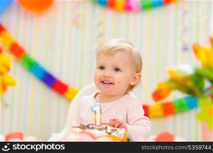 Portrait of eat smeared kid with first birthday cake