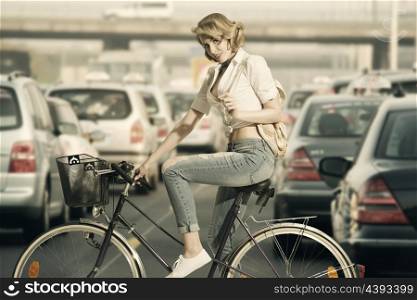 portrait of eco-friendly woman on a bicycle with casual style and small backpack in sensual pose looking in camera &#xA;