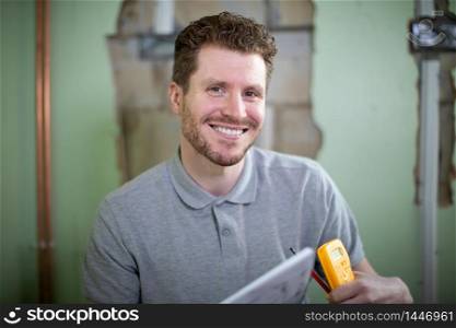 Portrait Of Electrician Inside House Being Renovated Studying Plans