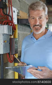 Portrait Of Electrician Standing Next To Fuseboard
