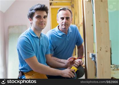 Portrait Of Electrician With Apprentice Working In New Home