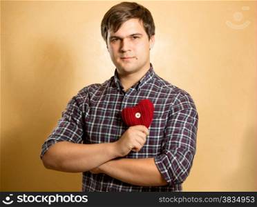 Portrait of elegant man holding red heart at chest