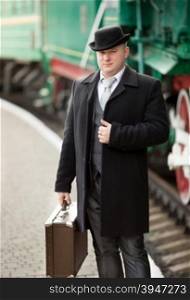 Portrait of elegant man in retro suit posing on railway station platform
