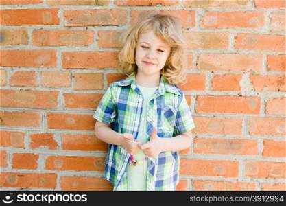 Portrait of emotional little girl in summer dress outdoor, brick wall behind