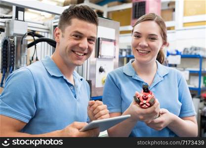 Portrait Of Engineer And Apprentice Examining Component In Factory