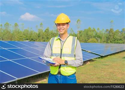 Portrait of engineer man or worker, people, with solar panels or solar cells on the roof in farm. Power plant with green field, renewable energy source in Thailand. Eco technology for electric power.