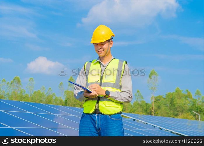 Portrait of engineer man or worker, people, with solar panels or solar cells on the roof in farm. Power plant with green field, renewable energy source in Thailand. Eco technology for electric power.