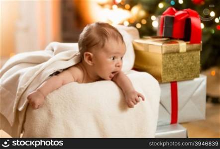 Portrait of excited baby boy looking on the stack of Christmas presents