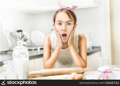 Portrait of excited girl clapping on her cheeks with flour while cooking