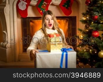 Portrait of excited woman posing with stack of Christmas gift boxes