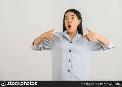Portrait of Excited young asian woman in blue shirt pointing finger at something isolated on white background. Expression and lifestyle concept.