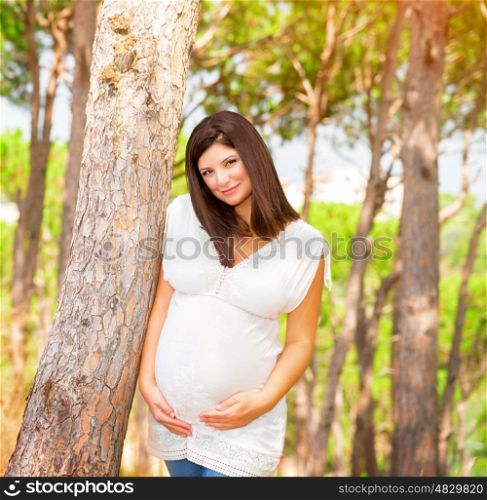 Portrait of expectant arabic female outdoors, spending time in garden in summer time, touching belly, happy and healthy pregnancy, love concept